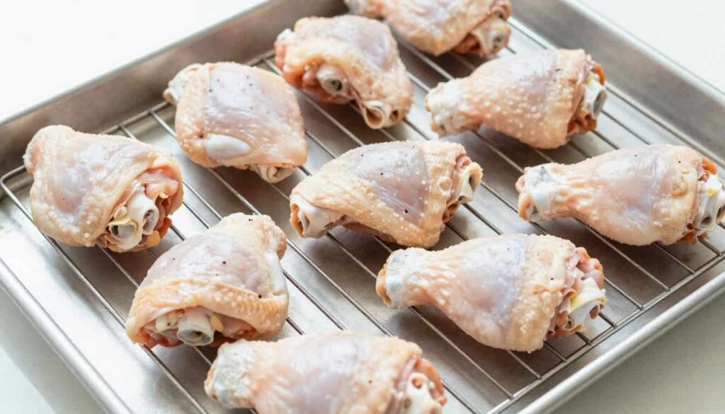 “Chicken thighs on a wire rack ready for oven roasting for extra crispiness”